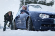 Woman in car watching man shoveling snow from around car