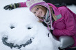 Woman making a face in snow on car windshield