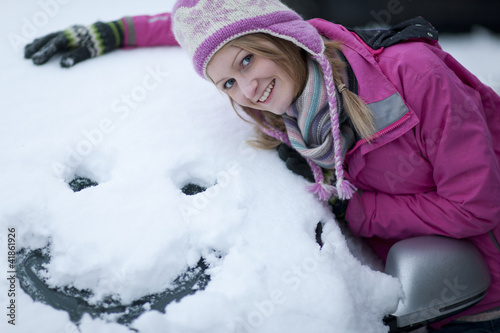 Photo: Woman making a face in snow on car windshield Woman making a face in snow on car windshield