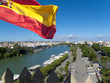 Spanish flag fluttering with city and river in background, Seville, Spain