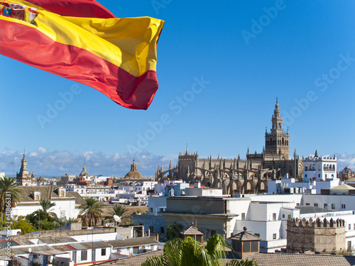Photo: Spanish flag fluttering with cathedral in background, Seville, Spain Spanish flag fluttering with cathedral in background, Seville, Spain