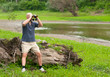 Slim bald man watching the nature through binoculars