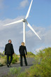 Man and woman in suit walking next to a wind turbine