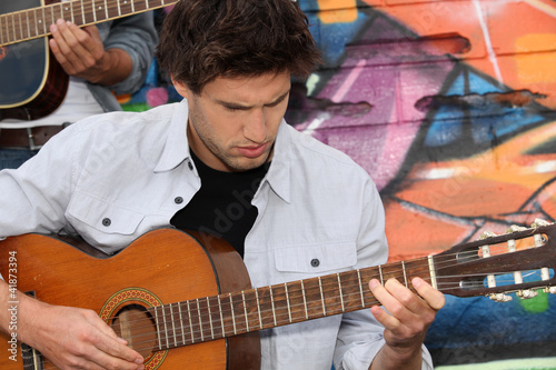 Photo: Musician with guitar in front of painted wall Musician with guitar in front of painted wall