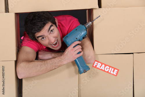Photo: Man with drill amongst boxes Man with drill amongst boxes
