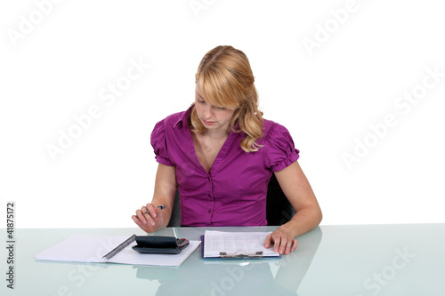 Photo: Woman using a calculator at work Woman using a calculator at work