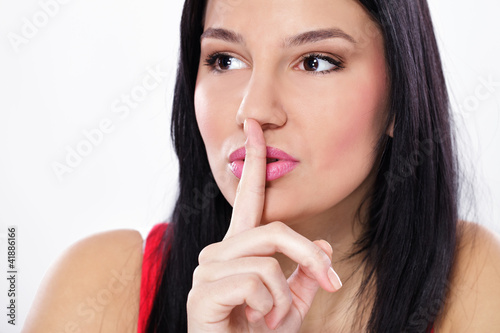 Photo: Young woman holding finger on lips Young woman holding finger on lips