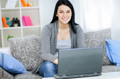 Photo: young girl with laptop computer, sitting in living room young girl with laptop computer, sitting in living room
