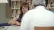Old woman reading newspaper with husband in library