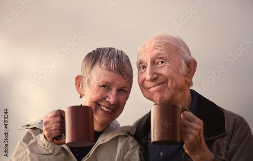 Photo: Smiling Senior Couple Toasting with Mugs Smiling Senior Couple Toasting with Mugs