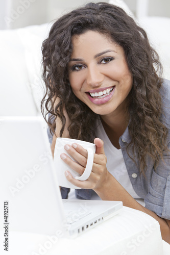 Photo: Woman Smiling Drinking Tea or Coffee Using Laptop Computer Woman Smiling Drinking Tea or Coffee Using Laptop Computer