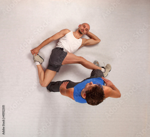 Photo: muscular man stretching with personal trainer in studio muscular man stretching with personal trainer in studio