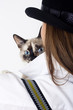 the cat looks out from behind the girl in the hat