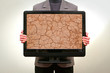 Man holding in hands lcd tv showing cracked clay ground Man holding in hands lcd tv showing cracked clay ground