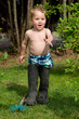 Kleiner Junge wandert mit Papas Gummistiefel