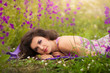Beautiful young woman in purple flowers outdoors