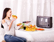 Woman eating fast food and watching TV.