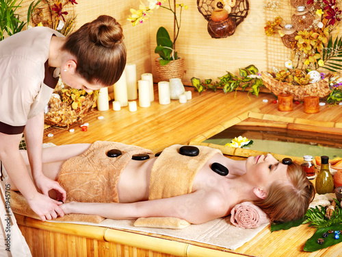 Photo: Woman getting stone therapy massage . Woman getting stone therapy massage .