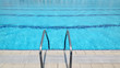 Swimming pool steel ladder and clear blue water