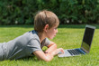 Foto: Junge mit Notebook auf einer Wiese Junge mit Notebook auf einer Wiese