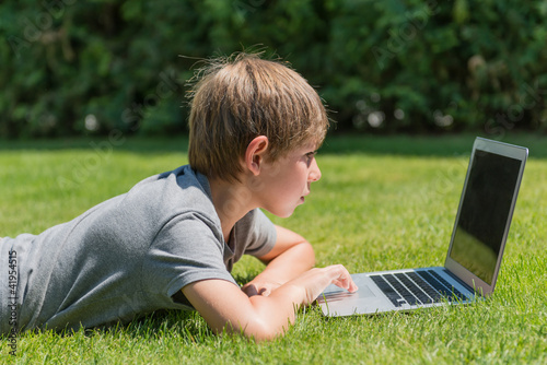 Photo: Junge mit Notebook auf einer Wiese Junge mit Notebook auf einer Wiese