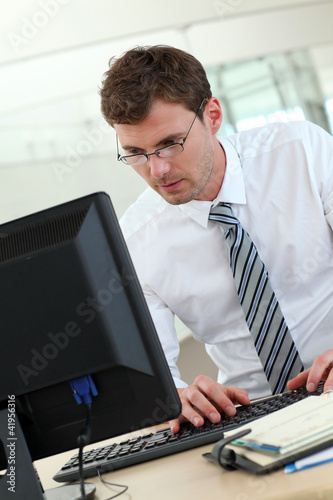 Photo: Portrait of businessman sitting at his desk in office Portrait of businessman sitting at his desk in office