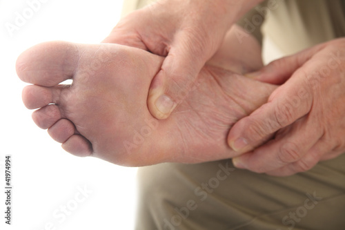 Photo: a man checks his aching foot a man checks his aching foot