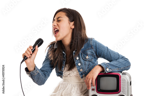 Photo: Preteen girl singing karaoke with microphone isolated on white Preteen girl singing karaoke with microphone isolated on white