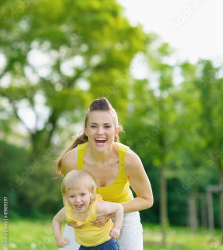 Photo: Portrait of happy mother and baby girl in park Portrait of happy mother and baby girl in park