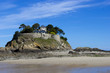 Landscape, seascape with beach and a house on top of a rock.