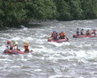 People in rubber boats sail down wildwater river