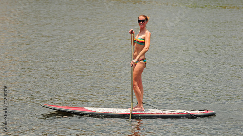 Photo: Woman getting exercise by paddleboarding Woman getting exercise by paddleboarding
