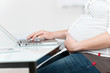 schwangere frau arbeitet am laptop
