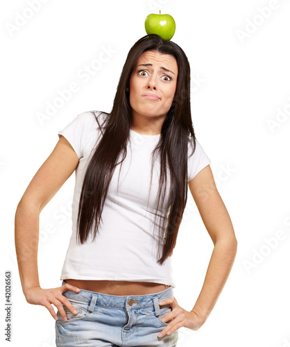 Photo: portrait of young woman holding green apple on her head over whi portrait of young woman holding green apple on her head over whi