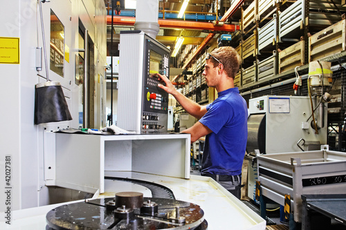 Photo: skilled worker controlling a digitally programmed machine tool skilled worker controlling a digitally programmed machine tool