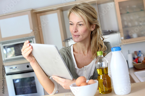 Foto: Woman in kitchen looking at dessert recipe on internet Woman in kitchen looking at dessert recipe on internet