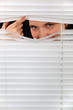 Woman peering through some blinds