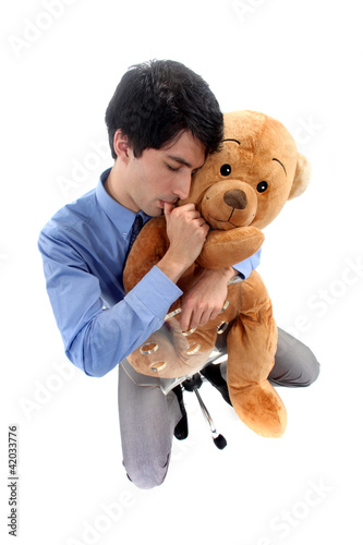 Foto: A businessman hugging a teddy bear. A businessman hugging a teddy bear.
