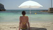 Young woman sitting on the beach under umbrella