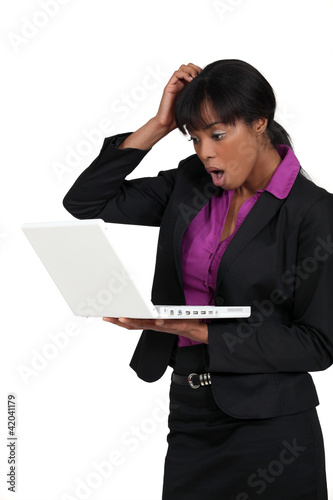 Photo: Businesswoman staring in shock at her laptop Businesswoman staring in shock at her laptop