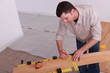 Man measuring plank of laminate flooring