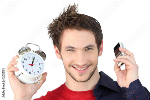 Photo: Man holding alarm clock and mobile telephone Man holding alarm clock and mobile telephone