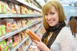 Foto: Happy blonde girl wearing white shirt chooses sausage Happy blonde girl wearing white shirt chooses sausage