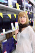 Foto: Blonde girl wearing scarf thinks about buying TV in supermarket; Blonde girl wearing scarf thinks about buying TV in supermarket;