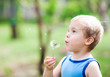 Cute boy blowing on a dandelion on a background of nature