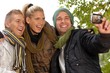Photo: Happy friends photographing themselves in park Happy friends photographing themselves in park