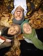 Photo: Happy people in autumn park laying among leaves Happy people in autumn park laying among leaves