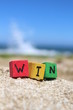 Photo: The word WIN written on wooden cubes, at the beach The word WIN written on wooden cubes, at the beach