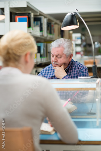 Photo: Senior man studying among young people in library Senior man studying among young people in library