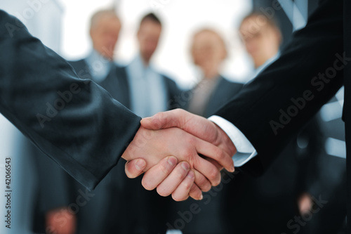 Photo: Handshake in front of business people Handshake in front of business people